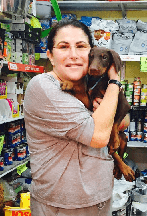Boca Raton Help owner holding a small dog in a local pet supply aisle